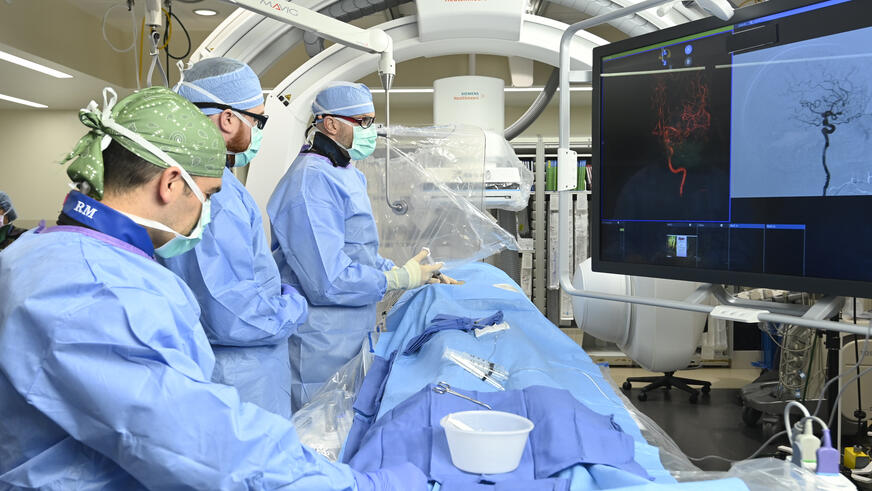 Neurology residents and attendings at work on a patient in the interventional suite