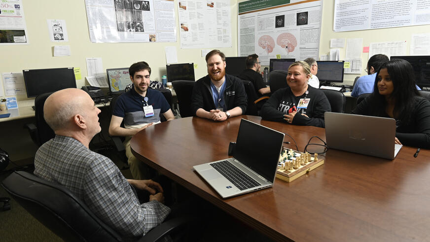 Neurology residents gathered around an attending at a table.