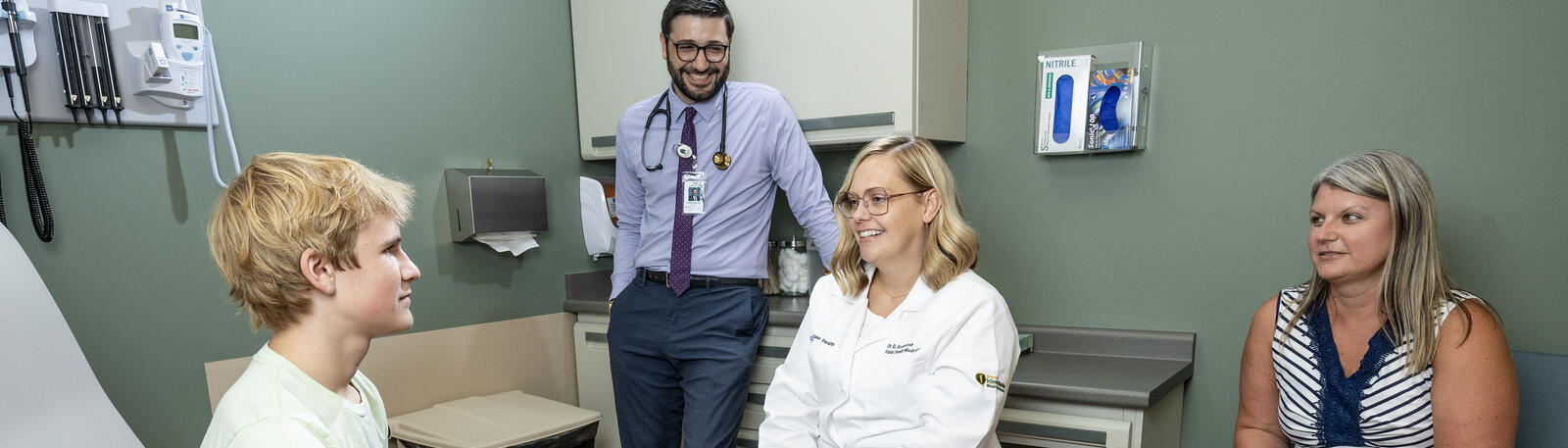 photo of a resident and physician with a patient and parent in an exam room