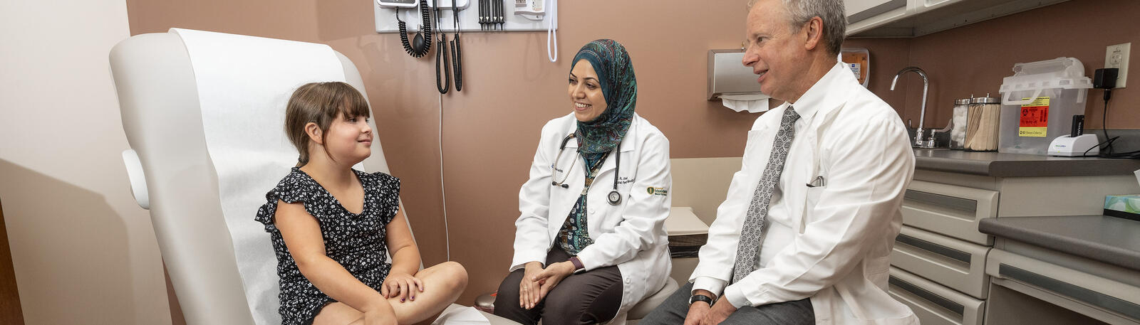photo of a resident and physician with a patient in an exam room