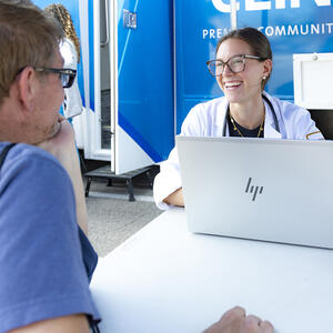 medical student and patient sitting at a table talking