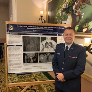 Presenter stands with his conference poster: Do not leave your radiologist in the dark: Pneumoscrotum after spontaneous bilateral pneumothoraces